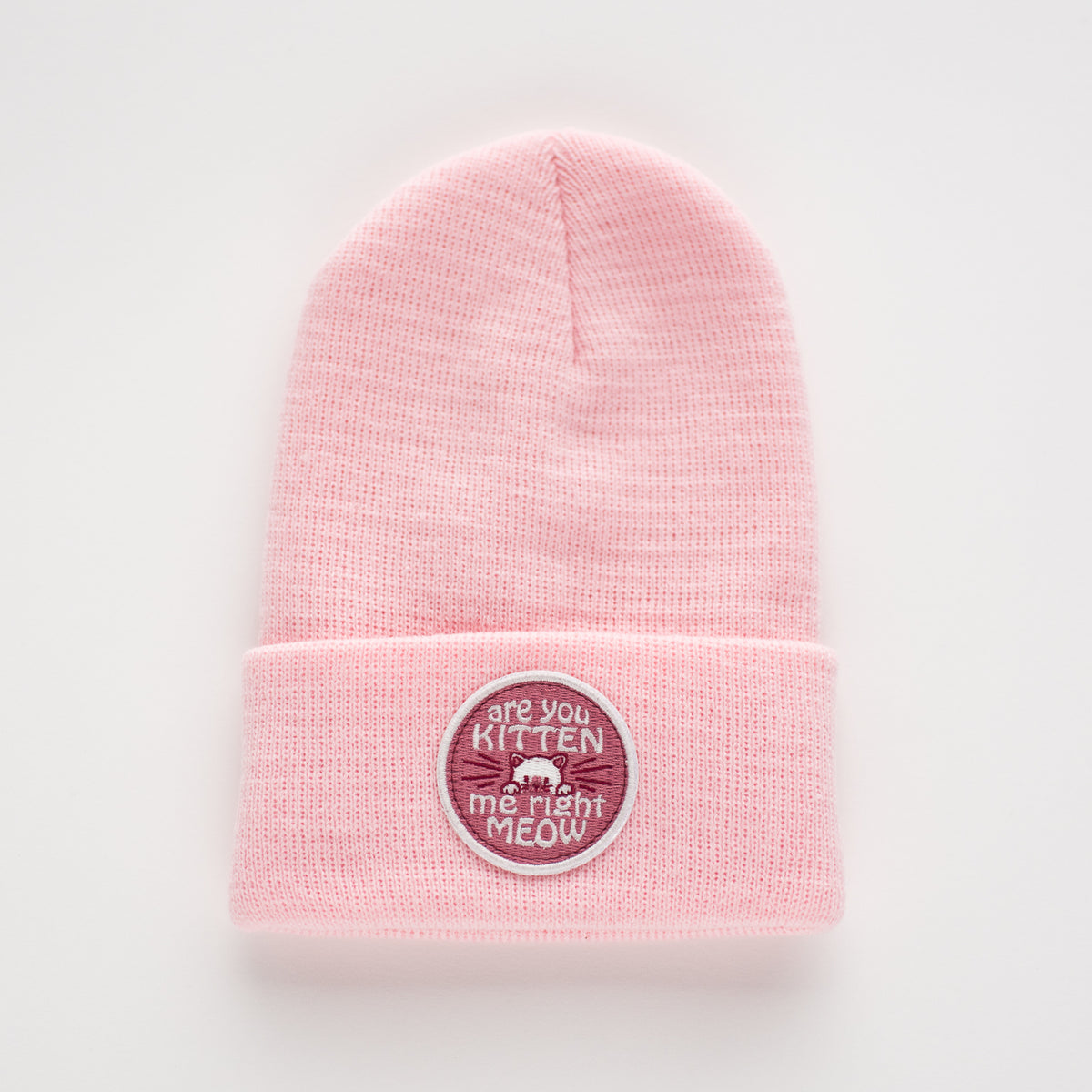The Peony Kids Beanie, crafted from acrylic, showcases a charming embroidered patch on the front. This patch features a cat face and the playful phrase "are you kitten me right meow.