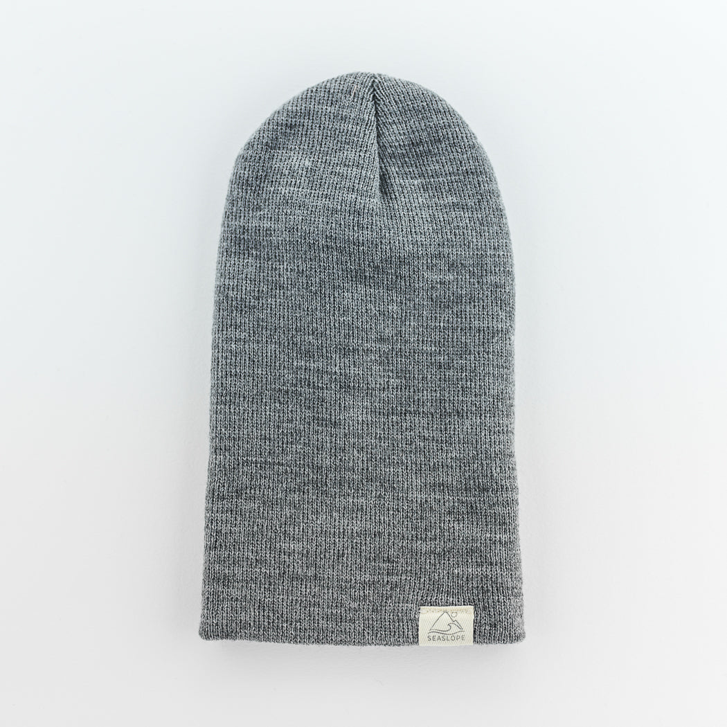 The STONE INFANT/TODDLER BEANIE by seaslope1 is a knitted hat designed for infants and toddlers. It offers a soft, stretchable fit and includes a small rectangular label with a simple design. The beanie is crafted from 100% acrylic material, giving it a subtle heathered texture.