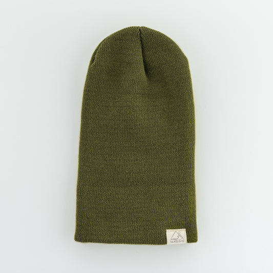 The infant/toddler beanie is a green knit hat designed for comfort and flexibility. It features a soft, stretch fit and has a small beige label on the brim, displayed against a light background.