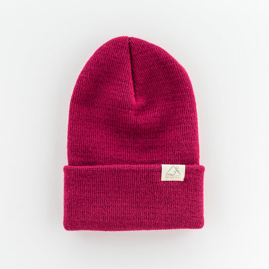 The TULIP INFANT/TODDLER BEANIE by seaslope1 is crafted from 100% acrylic in pink and is showcased against a plain white background. It features a folded brim and is adorned with a small rectangular tag on the front. Made in the USA, this beanie seamlessly blends style with quality.