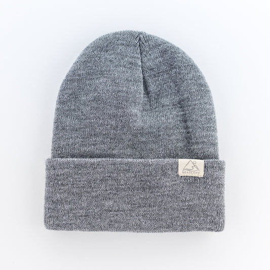 The STONE INFANT/TODDLER BEANIE by seaslope1 is displayed against a plain white background. This gray knit beanie, made from 100% acrylic, offers a soft stretch fit and features a folded brim adorned with a small rectangular tag.