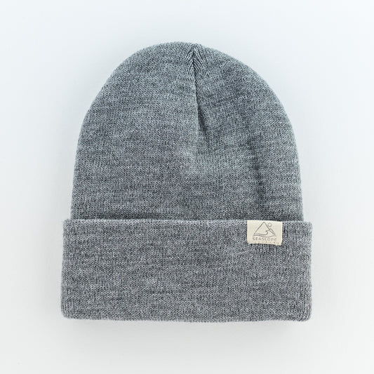 The STONE YOUTH/ADULT BEANIE by seaslope1, crafted from 100% acrylic, presents a gray knit design with a folded brim. It includes a small rectangular white tag and is displayed against a plain white background.