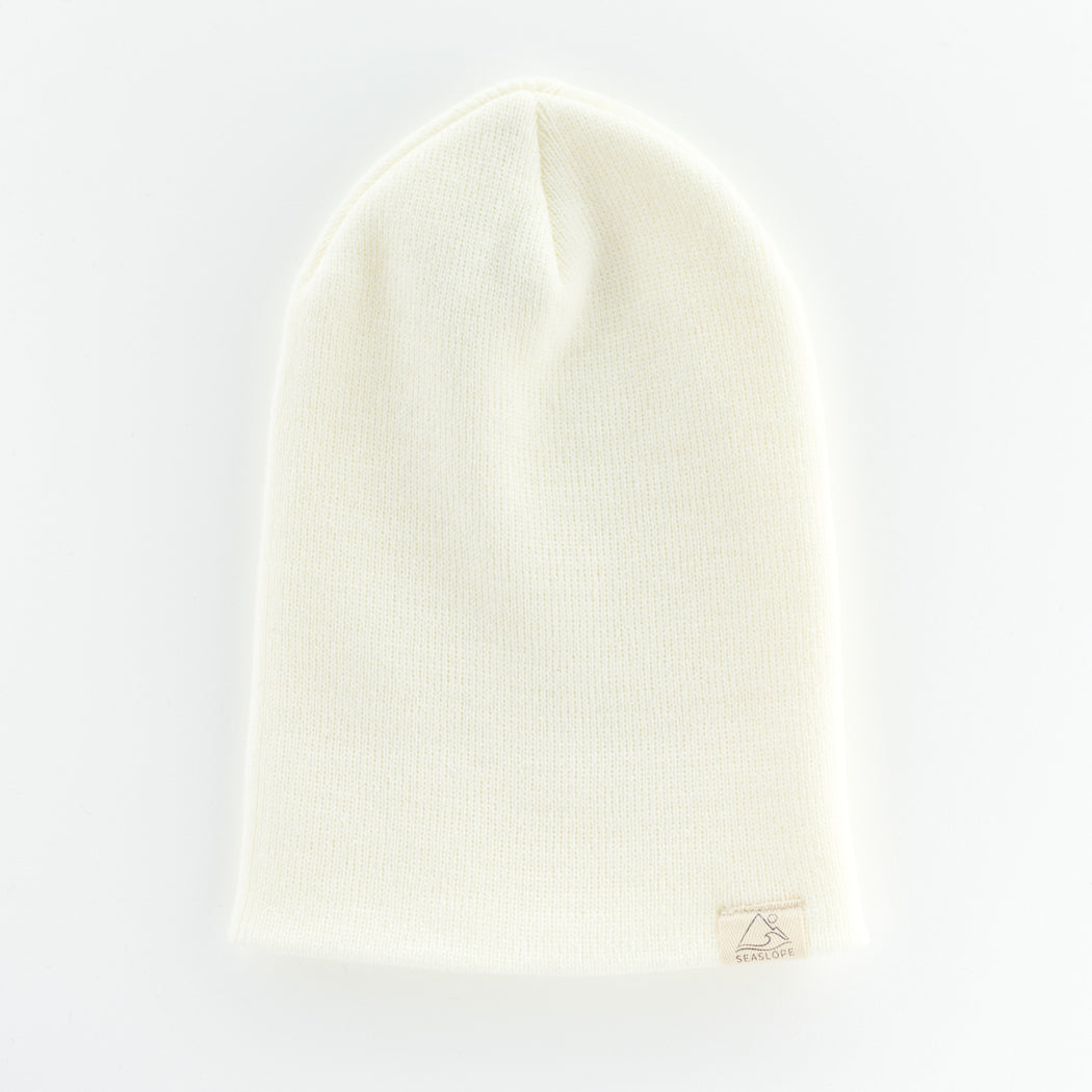 The DOVE YOUTH/ADULT BEANIE by seaslope1 is designed from soft acrylic fabric with a textured knit pattern. This beanie rests on a light surface and includes a small beige tag near the brim. It is crafted in the USA.