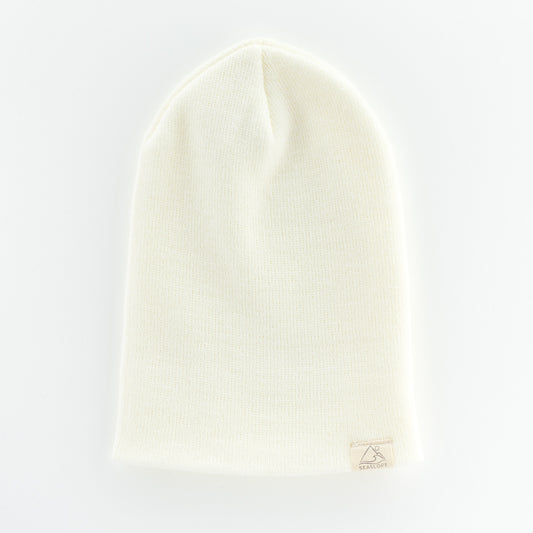 The DOVE YOUTH/ADULT BEANIE by seaslope1 is designed from soft acrylic fabric with a textured knit pattern. This beanie rests on a light surface and includes a small beige tag near the brim. It is crafted in the USA.