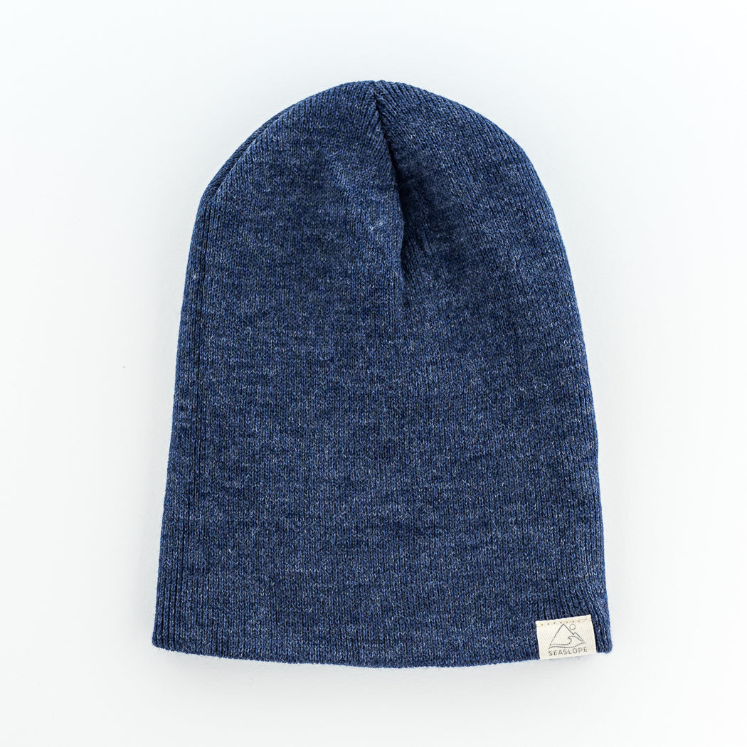 A blue DUSK YOUTH/ADULT BEANIE by seaslope1, made in the USA, is displayed flat on a white background. A small white fabric tag is stitched on one side.