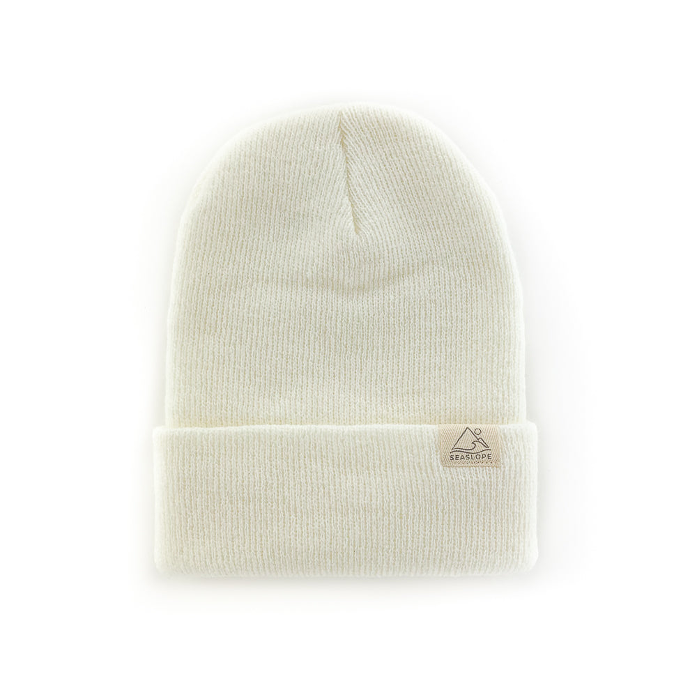 The DOVE INFANT/TODDLER BEANIE by seaslope1 is a stylish, cream-colored knit hat made from 100% acrylic. It features a folded brim and is made in the USA. This beanie is showcased against a plain white background.