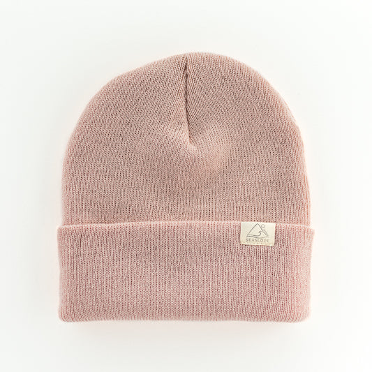 The ROSE YOUTH/ADULT BEANIE by seaslope1 is a light pink acrylic knit hat with a folded cuff. Made in the USA, its simple and cozy design is highlighted when displayed flat on a light background.