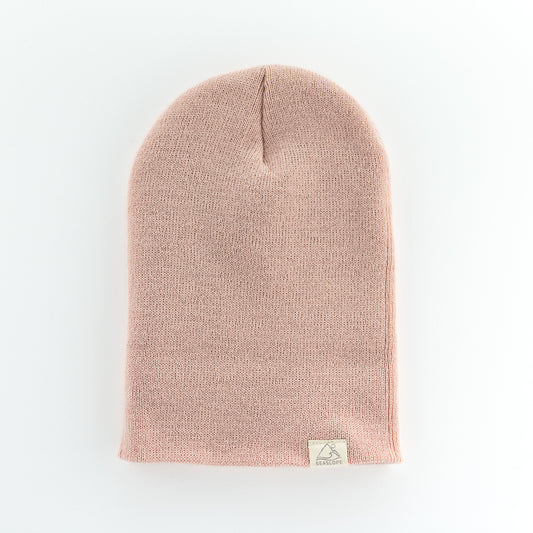 The ROSE YOUTH/ADULT BEANIE by seaslope1 is an acrylic knit beanie in pink, set against a white backdrop. It includes a small beige tag and is proudly made in the USA.