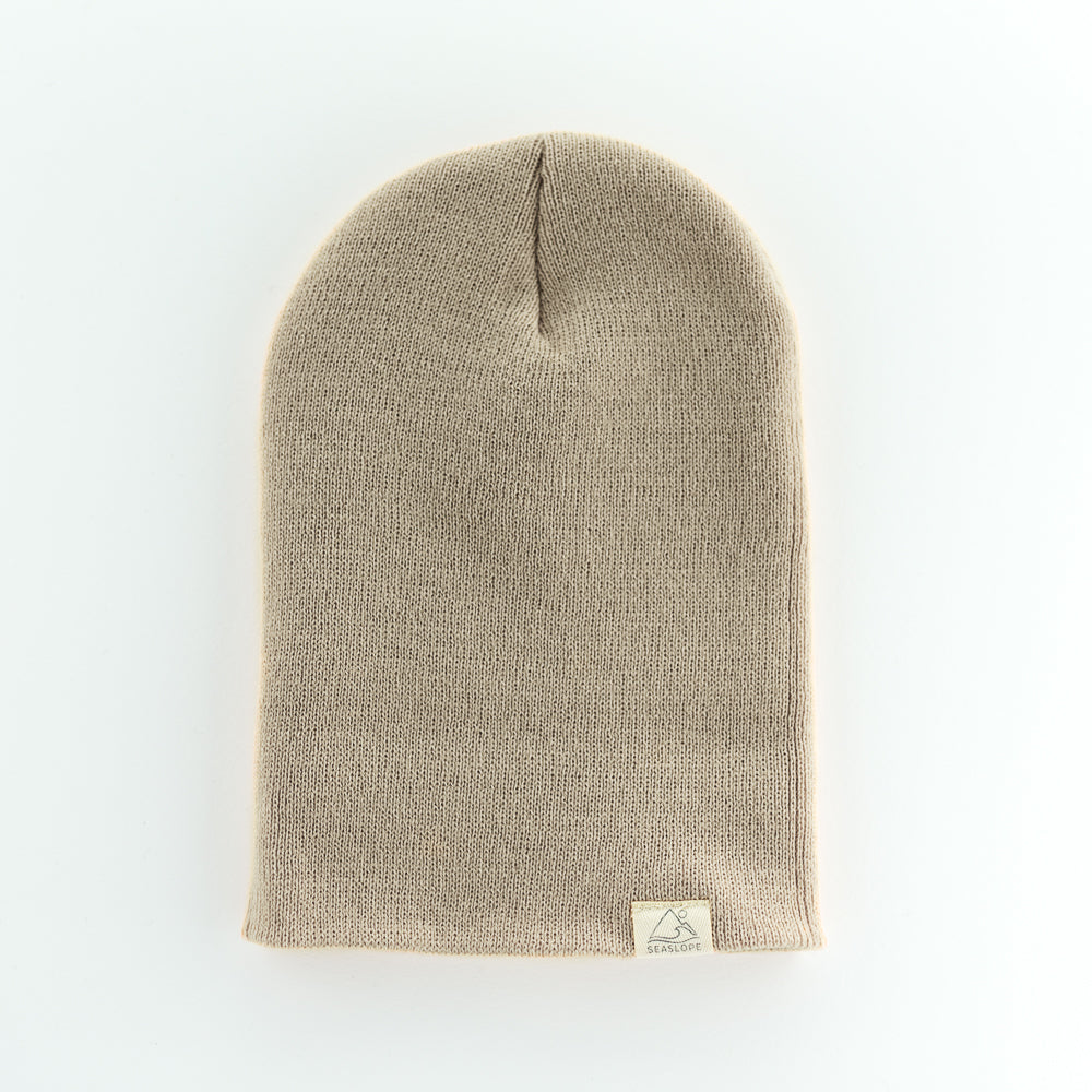 The SAND YOUTH/ADULT BEANIE by seaslope1 is crafted from 100% acrylic in a beige knit. It features a folded brim and is shown on a plain white background.