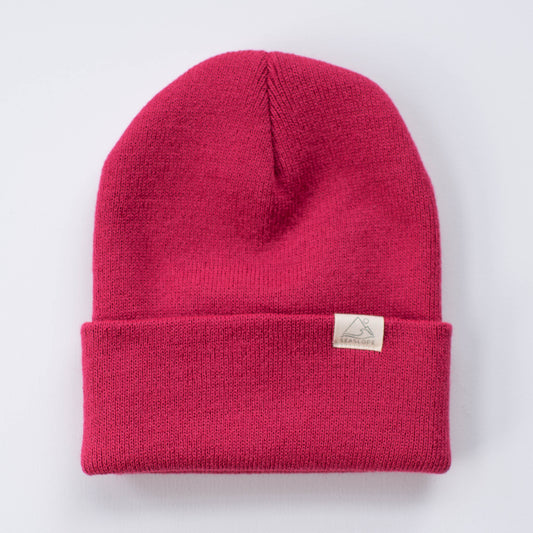 A red beanie designed for youth and adults by seaslope1 rests on a white surface. It is made from 100% acrylic and features a small rectangular label on the folded brim.