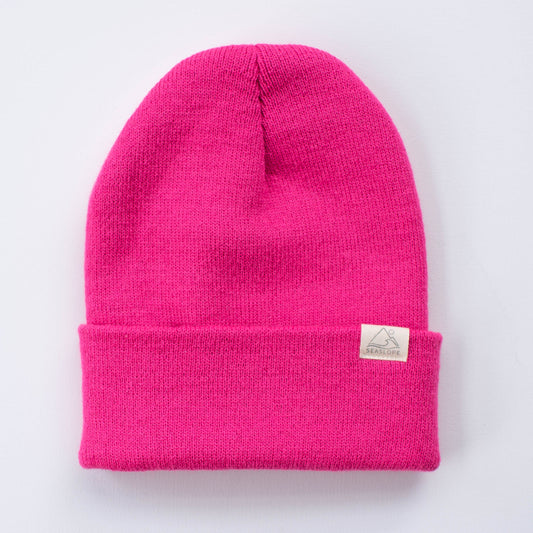 The FUCHSIA YOUTH/ADULT BEANIE by seaslope1 showcases a vibrant pink knit design with a folded cuff. Stylishly displayed on a white background, it is the ideal accessory for adding both warmth and flair.