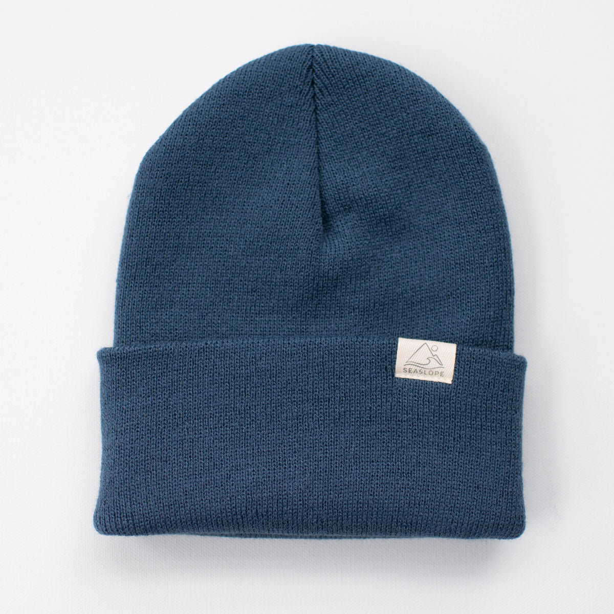 The MARINE YOUTH/ADULT BEANIE by seaslope1 is crafted from 100% acrylic and made in the USA. This blue marine knit beanie features a folded brim and a small white rectangular patch with text on the brim. It is stylishly presented on a plain white background.