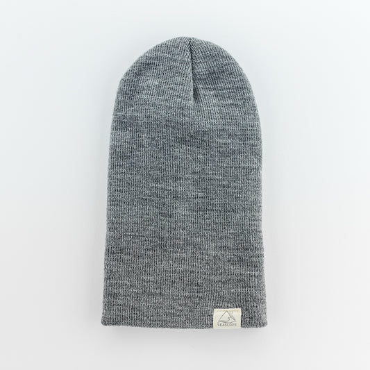 The STONE INFANT/TODDLER BEANIE by seaslope1 is a knitted hat designed for infants and toddlers. It offers a soft, stretchable fit and includes a small rectangular label with a simple design. The beanie is crafted from 100% acrylic material, giving it a subtle heathered texture.